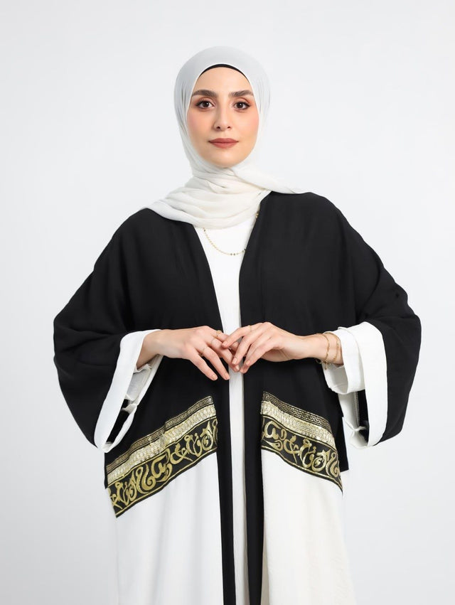 طقم عمرة "عود" — كارديجان أسود في أبيض بتطريز ذهبي + فستان بيزك أبيض